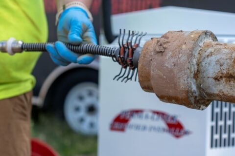 débouchage canalisation Nivelles : Plombier à Nivelles inspectant des canalisations murales dans une pièce technique