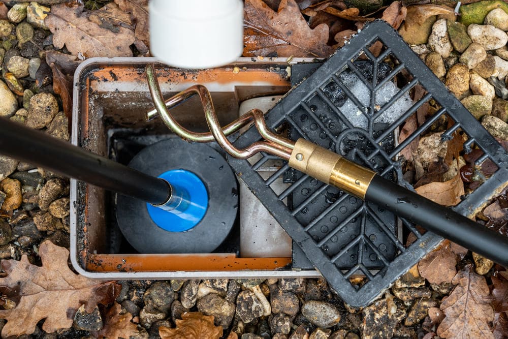 Technicien effectuant un débouchage de canalisation à Waterloo dans un local technique avec des tuyaux en PVC