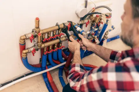 Technicien effectuant un débouchage de canalisation à Waterloo dans un local technique avec des tuyaux en PVC