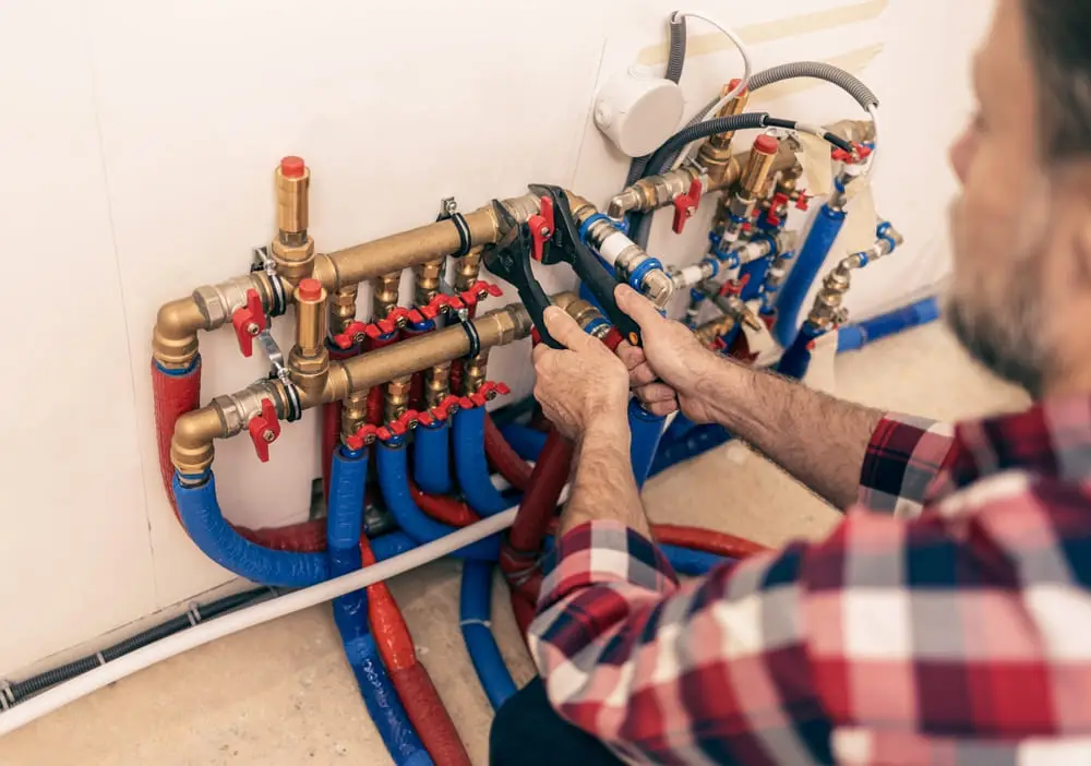 Technicien effectuant un débouchage de canalisation à Waterloo dans un local technique avec des tuyaux en PVC