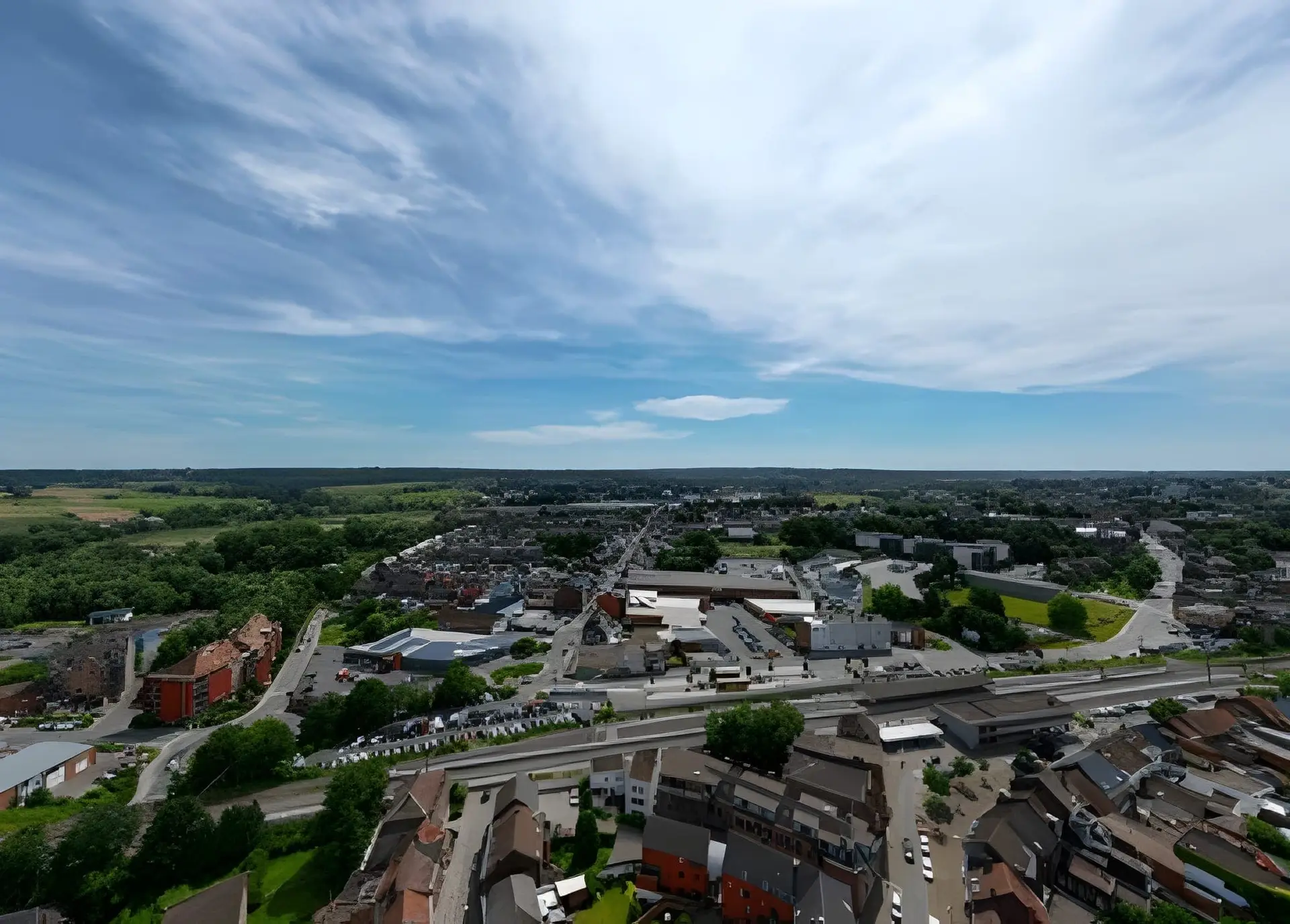 Tubize, Belgique, vue Aérienne capturant un paysage urbain mêlant constructions et verdure harmonieusement sous un ciel sans nuages et céruléen