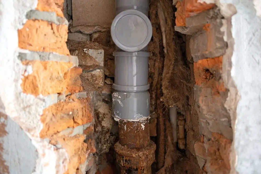 Débouchage Etterbeek : Réparation de canalisation d'égout. Remplacement partiel de l'ancien tuyau en fonte par un nouveau tuyau en plastique.